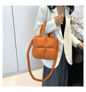 Sac à bandoulière matelassé orange tendance porté avec une tenue de blazer blanc décontracté