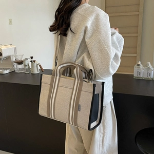 Detail of canvas tote with striped straps and side pocket in a coffee shop setting