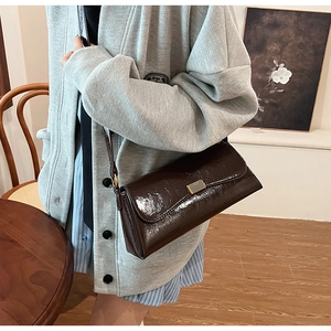 Close-up of a vintage dark brown oil wax leather shoulder bag with a gold metal clasp