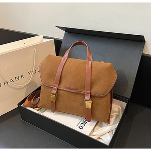 Detail view of a vintage brown frosted suede satchel bag inside a black luxury gift box