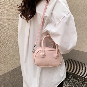 Mini borsa rosa con stampa coccodrillo, dettaglio cuore e tracolla indossata da modella
