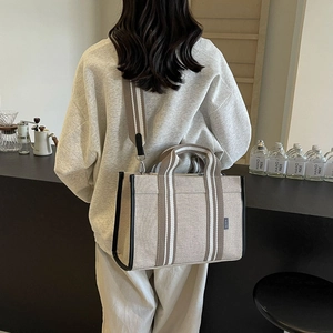 Detail of canvas tote bag with leather trim and adjustable striped shoulder strap