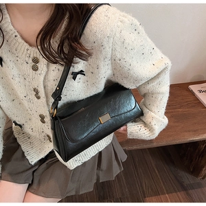 Close-up of black retro pleated baguette bag with a stylish gold square metal buckle