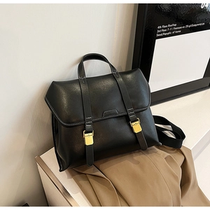 Detail view of black vintage leather briefcase with white stitching and gold metal buckle