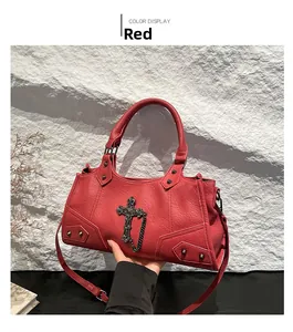 Detail view of red faux leather handbag with vintage metal cross and punk rivets