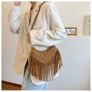 Détail du sac en daim marron avec rivets dorés et design élégant de franges vintage