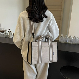 Detail of canvas tote bag with striped woven handles and detachable shoulder strap