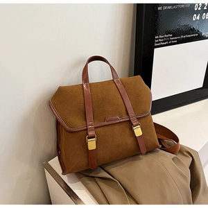 Close-up of brown suede messenger bag with gold buckles and leather trim detail