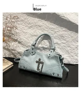 Close-up of light blue leather bag featuring silver cross pendant and rivet details