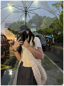 Street style shot of large white quilted cloud bag with puffy texture in rainy day scene