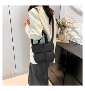 Détail d'un sac bandoulière matelassé noir en tissu duvet avec poignée souple et bandoulière