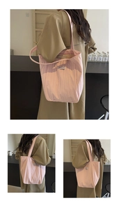 Detail of pink pleated tote bag showing vertical stripe texture and small logo label