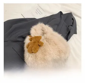 Detail of beige heart-shaped plush handbag with a cute brown teddy bear charm accessory