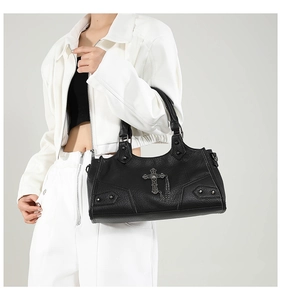 Detail of black faux leather tote with metal cross pendant and rivet studs on shoulder bag