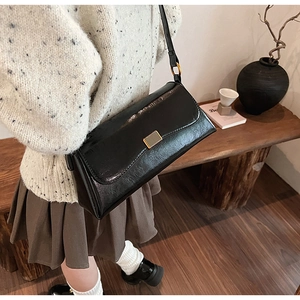 Detail view of a black retro shoulder bag with a gold rectangular metal buckle close-up