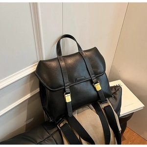 Detail of black vintage satchel showing gold buckles, leather texture, and wide shoulder strap