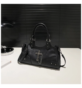 Close-up of black punk motorcycle bag with metal cross charms and pebbled faux leather texture