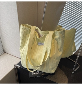 Detail of lime green pleated tote bag featuring vertical textures and white logo label