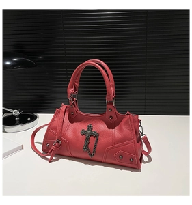 Detail of red punk motorcycle bag featuring metallic cross charms and rivet studs