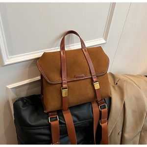 Detail of vintage brown suede backpack featuring leather straps and golden metal buckles