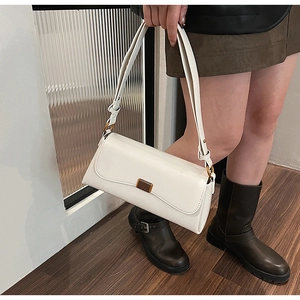 Close-up of a white faux leather shoulder bag with a gold metal clasp and adjustable strap