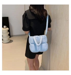Gros plan d'un sac matelassé bleu clair avec coutures quadrillées sur un mannequin