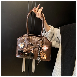 Détail de sac à main en cuir marron foncé avec broderie vintage 1979 et écusson d'aigle