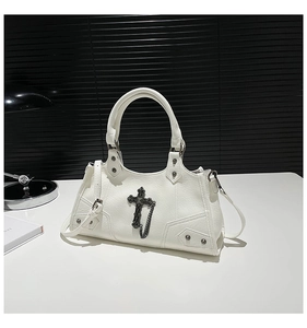 Detail shot of white motorcycle bag with punk cross pendant and metal rivet accents