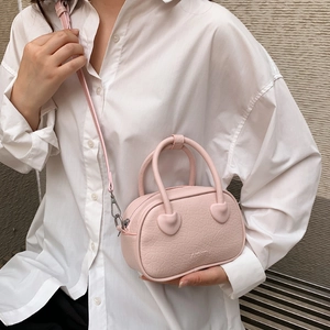 Dettaglio borsa in pelle litchi rosa con attacchi a forma di cuore e logo fashion sulla parte frontale