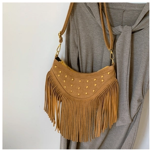 Détail du sac à bandoulière en daim marron à franges avec rivets dorés sur robe grise