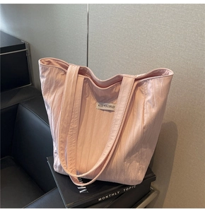 Close-up of pink crinkled tote bag featuring a slogan patch on high-quality fabric