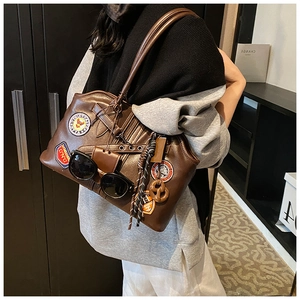 Gros plan d'un sac à bandoulière marron vintage avec écussons brodés et accessoire de lunettes