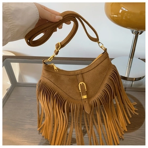 Détail d'un sac bohème en daim marron avec de longues franges et des boucles dorées