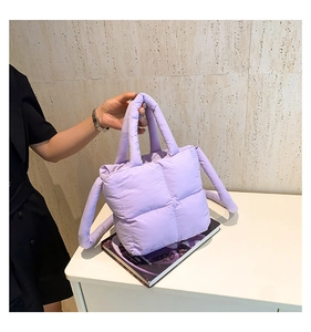 Gros plan d'un sac à main matelassé violet clair avec des poignées rondes rembourrées