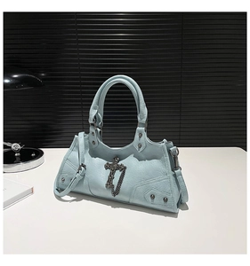 Close-up of baby blue bag with metal cross, chain details and silver rivets