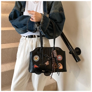 Détail d'un sac à main rétro noir avec écussons brodés vintage et breloques de mode élégantes