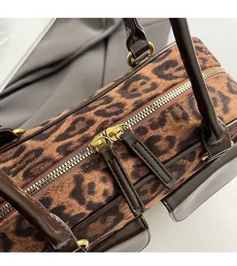 Detail of smooth metal double zipper and brown leather trim on leopard print handbag