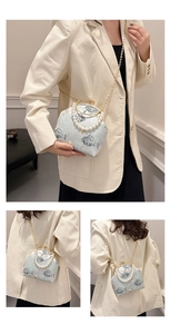 Detalle de bordado floral en bolso de seda azul claro con asa de perlas y cadena dorada