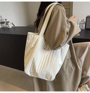 Detail view of white pleated canvas tote bag showing the unique vertical texture and shoulder strap