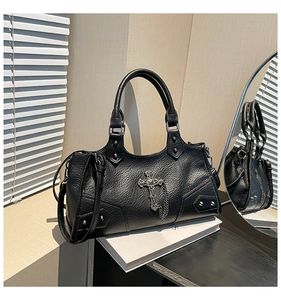 Close-up of black PU leather bag featuring silver rivets and a gothic cross pendant