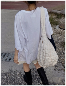 White quilted puffer cloud bag with textured padding shown in a stylish outdoor setting