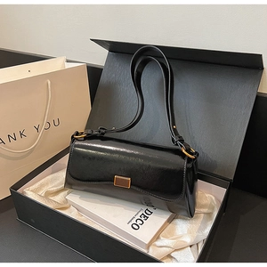 Elegant black shoulder bag with gold hardware in a gift box with white satin lining
