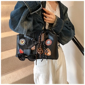 Détail du sac cabas en cuir noir avec écussons brodés et breloques en forme de bretzel
