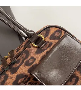 Close-up of leopard print suede bag featuring brown oil wax leather handles and gold hardware
