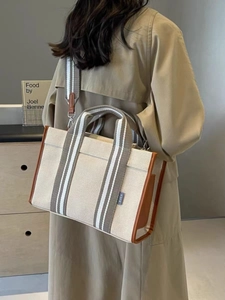 Large beige canvas tote bag with brown leather trim and adjustable crossbody strap