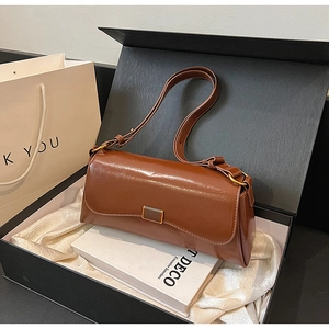Detail of caramel brown leather shoulder bag with gold buckle in black gift box