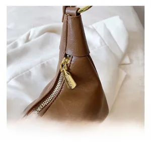 Close-up of high-quality golden metal zipper and brown leather texture on a shoulder bag