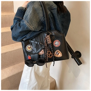 Détail d'un sac à bandoulière vintage en cuir PU noir avec écussons brodés de style sport