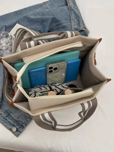 Large beige canvas tote bag showing spacious interior with tablet and umbrella storage