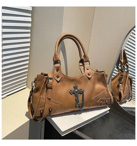Detail view of caramel faux leather bag with punk metal cross and vintage rivets